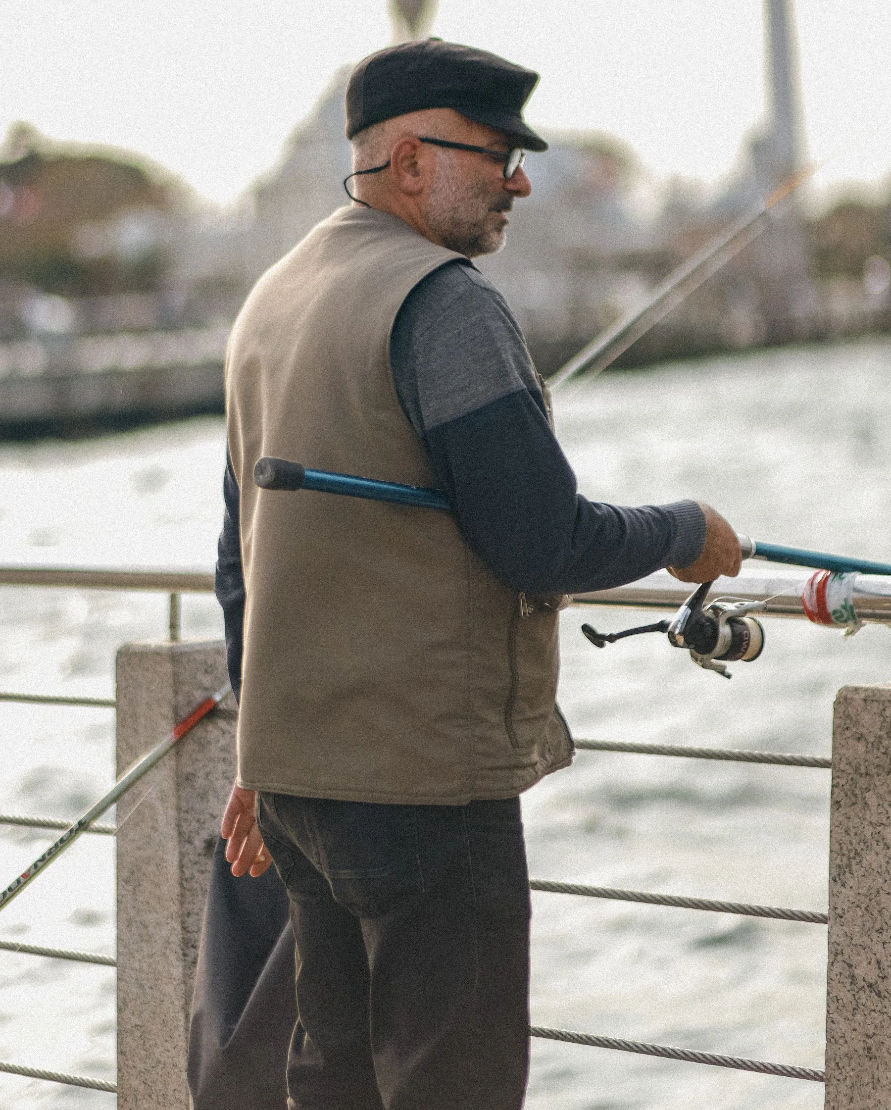 Man fishing with a rod supported on a riverside railing.