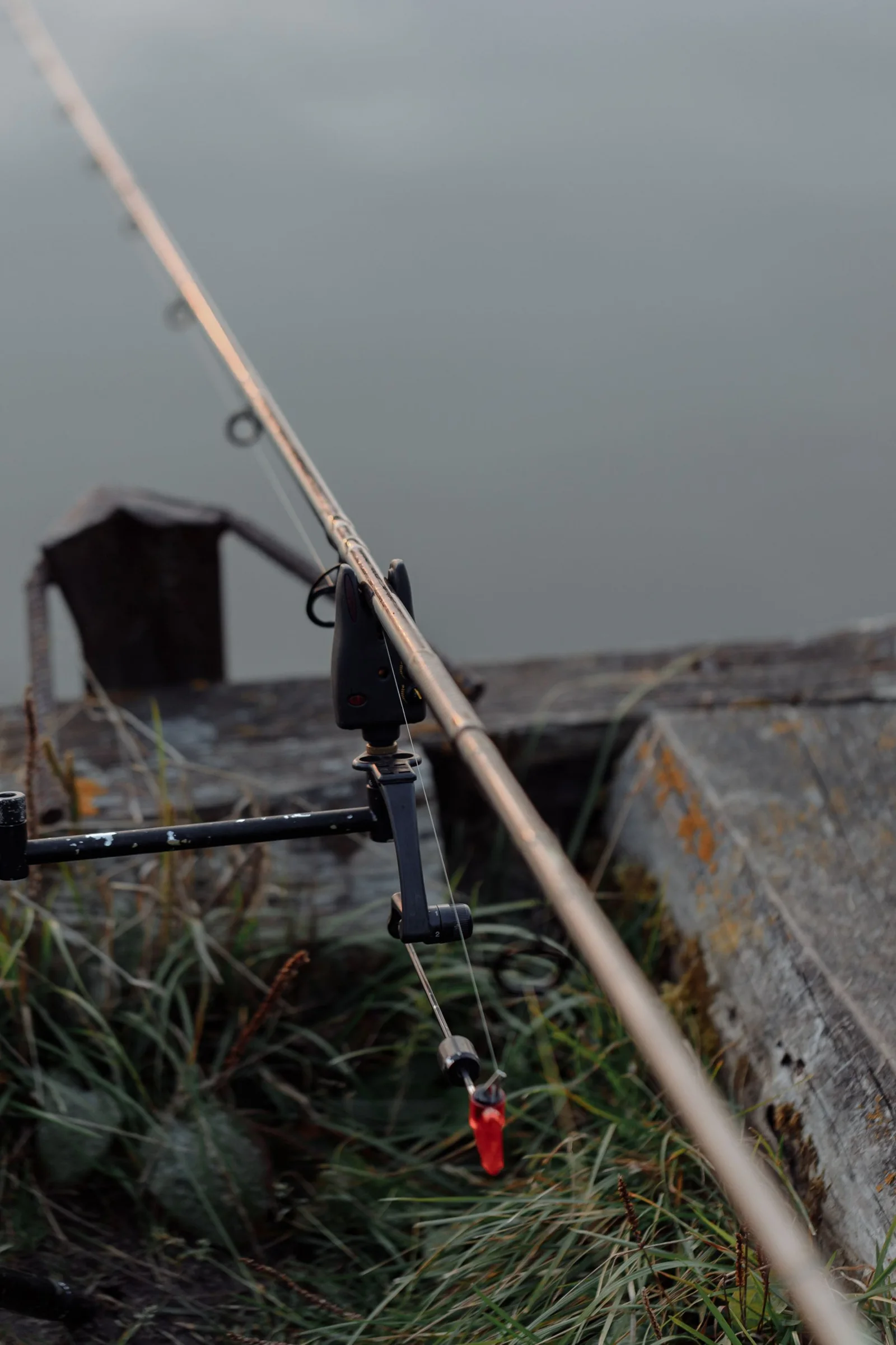 Fishing rod and equipment set beside a riverbank.